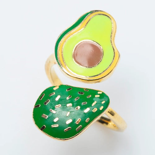 Gold ring that wraps around the finger. Each side has a different art element. One side has an avocado cut in half, and the other side is the skin-side of an avocado.