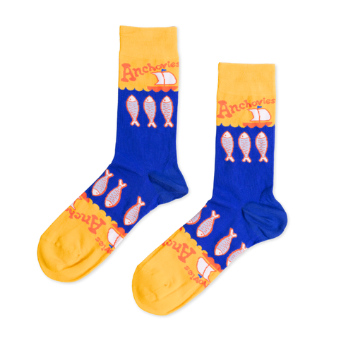 Blue and yellow crew socks featuring illustrated anchovies and Anchovies text with sailboat by Yellow Owl Workshop