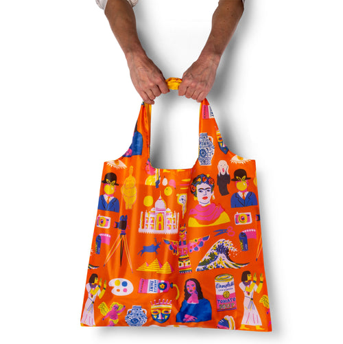 Person holding orange illustrated art history tote bag with folk art cut-paper print by The Printed Peanut for Yellow Owl Workshop