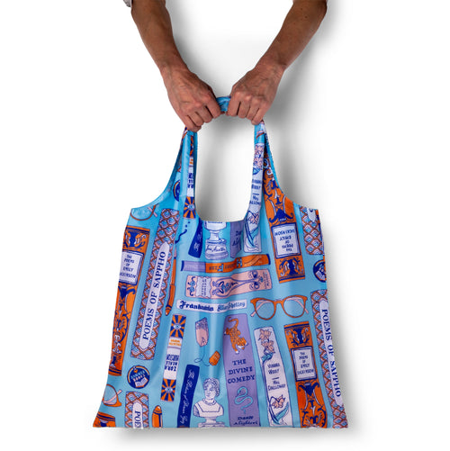 Person holding illustrated literary tote bag featuring banned books and female and queer authors by Yellow Owl Workshop
