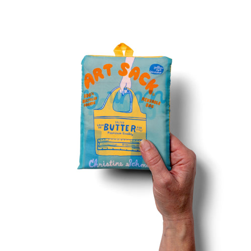 Person holding yellow illustrated butter tote bag with salted butter wrapper label design by Yellow Owl Workshop