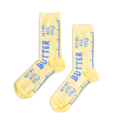 Yellow crew socks designed to look like a butter wrapper with bold blue Butter label and Net Wt 4 oz text by Yellow Owl Workshop