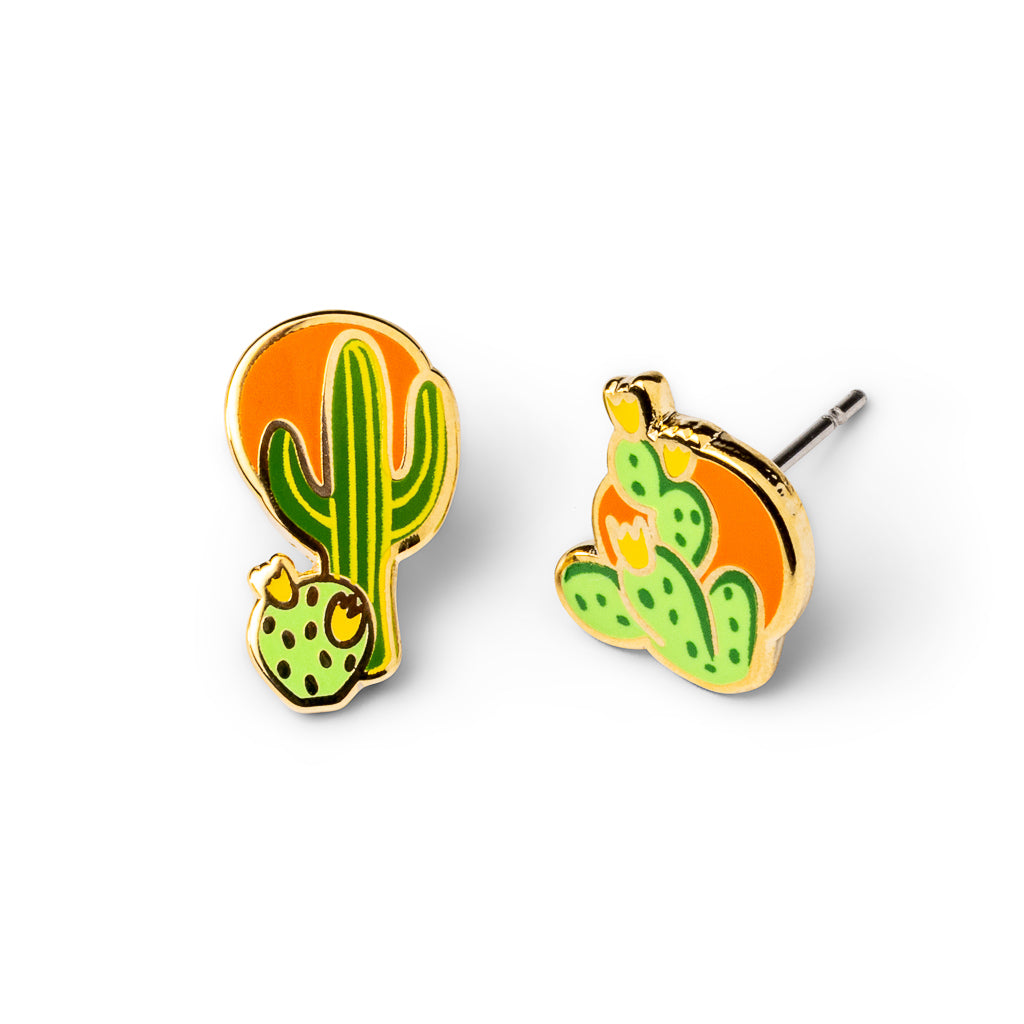 Mismatched cloisonné stud earrings featuring flowering saguaro and prickly pear cacti against orange desert sun gilded in 22 karat gold by Yellow Owl Workshop