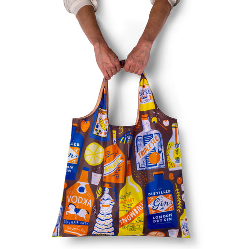 Person holding illustrated cocktail tote bag with vintage spirit bottle print by The Printed Peanut for Yellow Owl Workshop