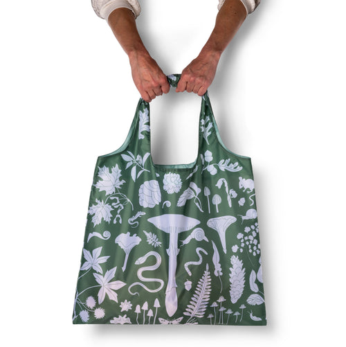 Person holding green illustrated woodland tote bag with white mushroom and botanical print by Banquet Workshop for Yellow Owl Workshop