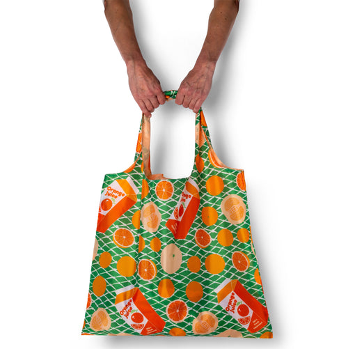 Person holding a reusable bag with orange and green pattern on a white background