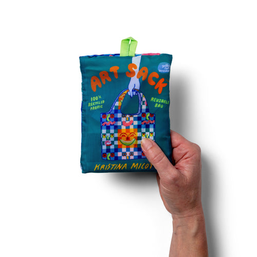 Person holding illustrated picnic tote bag with colorful playful food print by Kristina Micotti for Yellow Owl Workshop