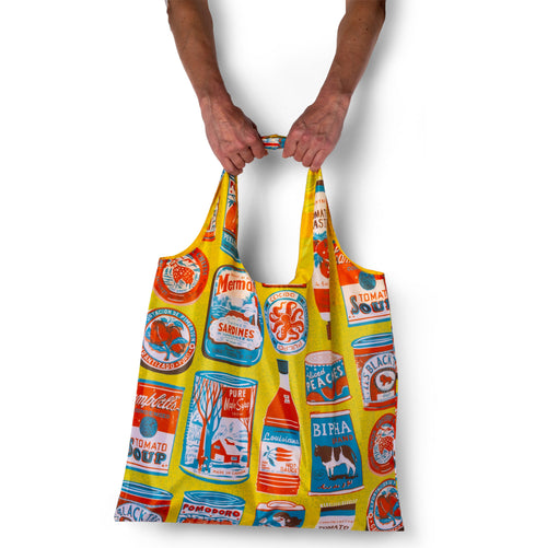 Person holding yellow illustrated reusable tote bag with vintage food can print by The Printed Peanut for Yellow Owl Workshop