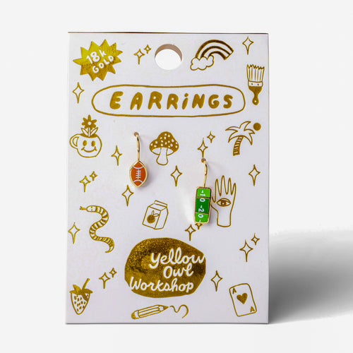 A pair of drop earrings, one shaped like a football with yard lines, the other shaped like a football with a different yard line design. 