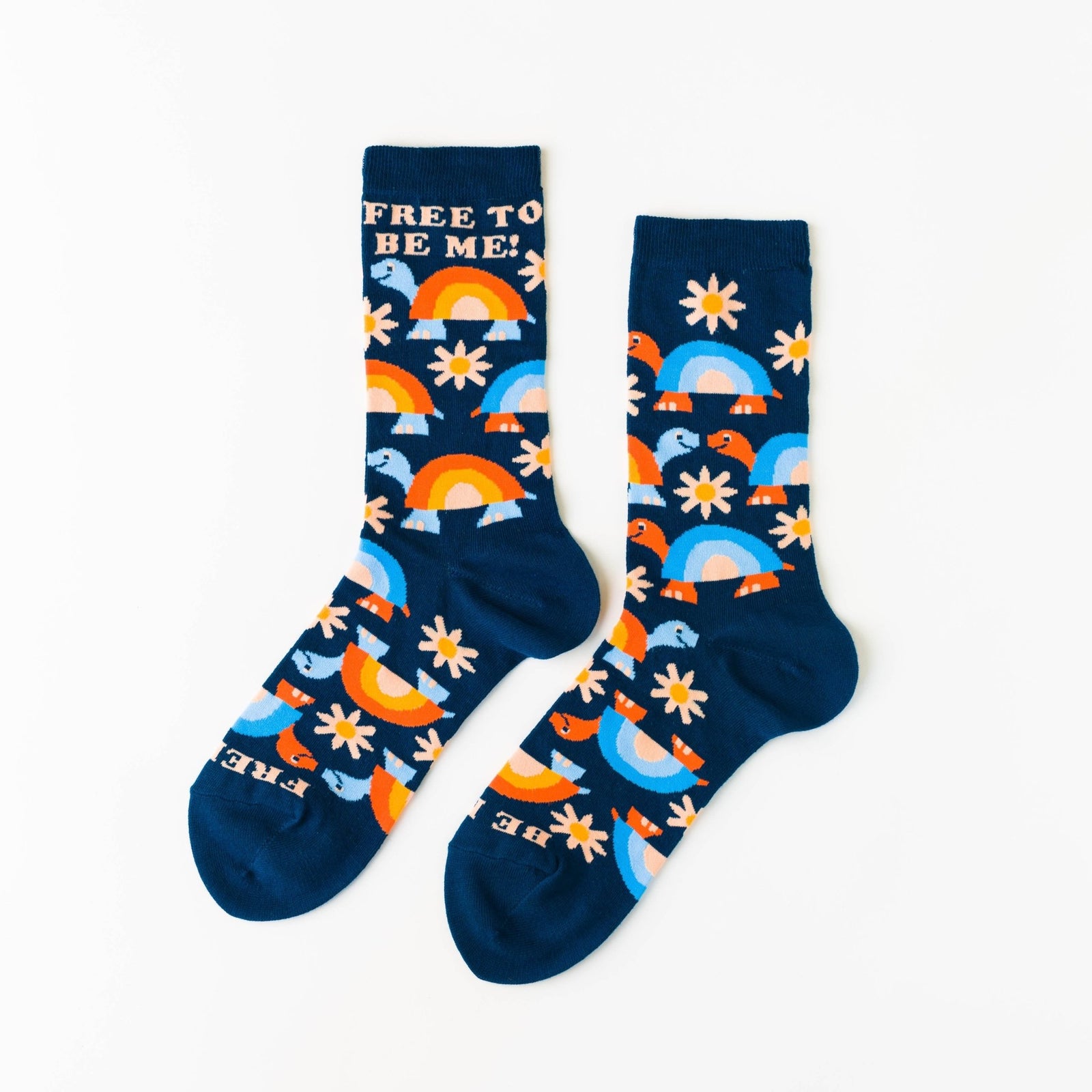 Navy crew socks featuring turtles rainbows and daisies with Free to Be Me text at cuff by Yellow Owl Workshop
