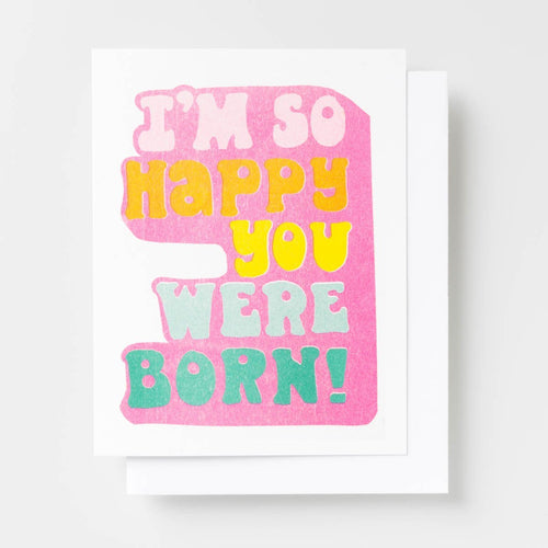 Risograph greeting card with bold retro typography in pink, yellow, and teal reading I'm So Happy You Were Born on a hot pink background